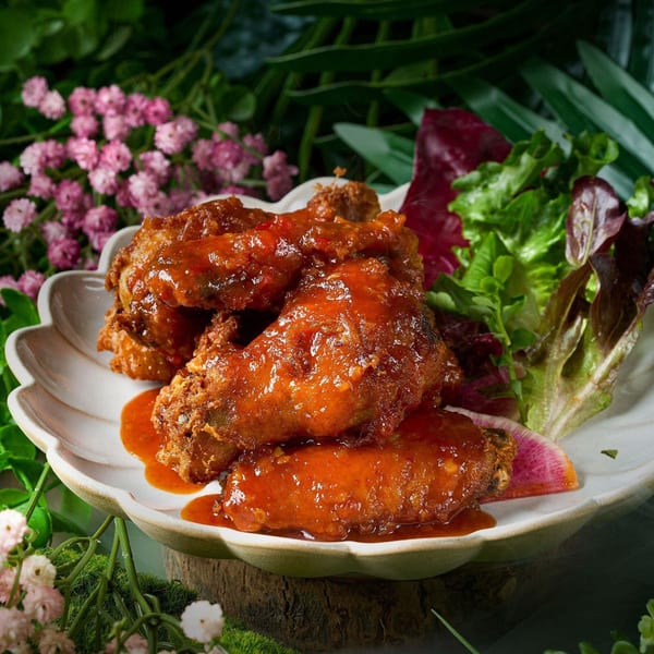 Crispy Thai chicken wings coated in a sweet chili sauce, served with fresh salad greens.