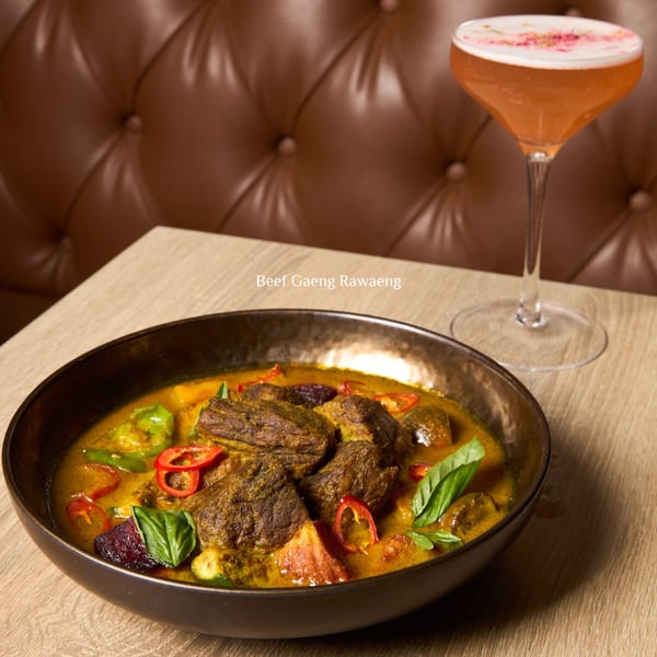 Khaosan's Beef Gaeng Rawaeng, a Thai curry with beef, basil, and chili, next to a cocktail.