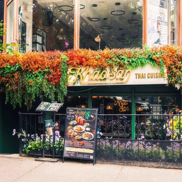 Khaosan Thai Cuisine restaurant exterior with a gold sign, vibrant orange and green floral decor, and a menu board.